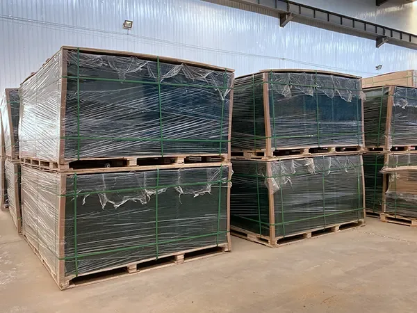 Wrapped green fence panels stacked in timber-framed pallet bundles